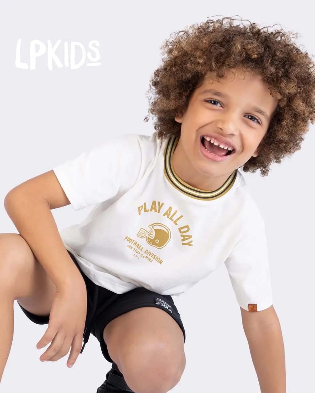 Menino sorrindo com um look da Alnitak